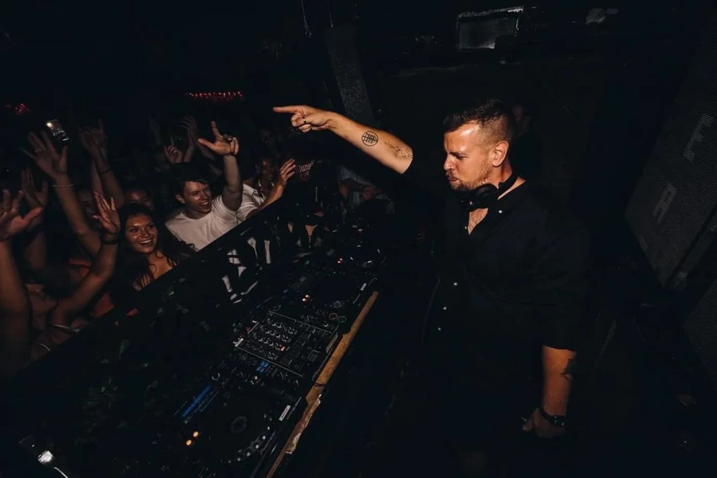 Eli Bury in the booth, pointing out at a full floor